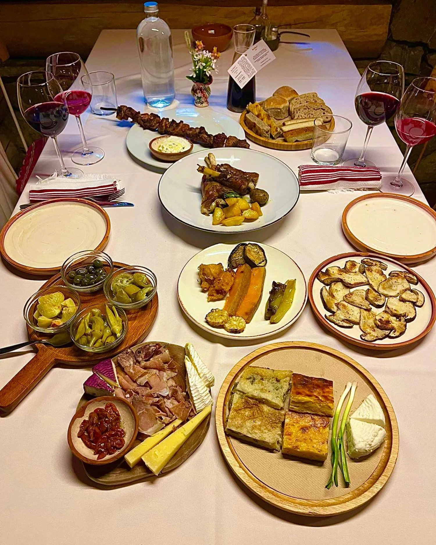 Albanian mountain feast — byrek, lamb, charcuterie, cheese and red wine at a guesthouse table