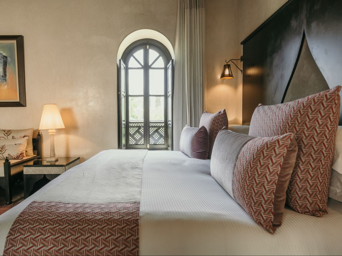 Riad bedroom with arched Moroccan window and terracotta fabrics