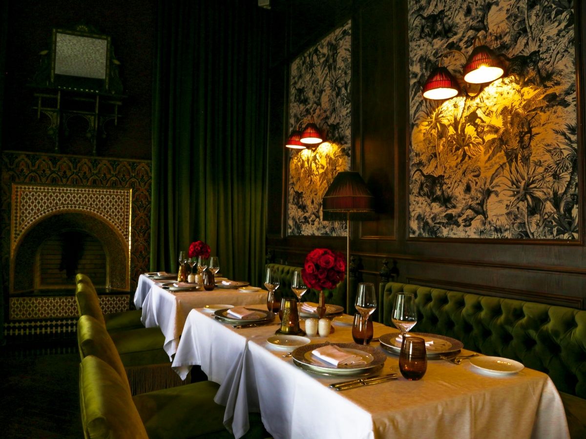 Elegant Fez restaurant — green velvet banquettes and zellige fireplace