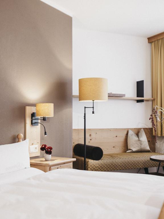 Lesachtal guesthouse room — Zirbenholz pine, warm linen lamp, alpine bench