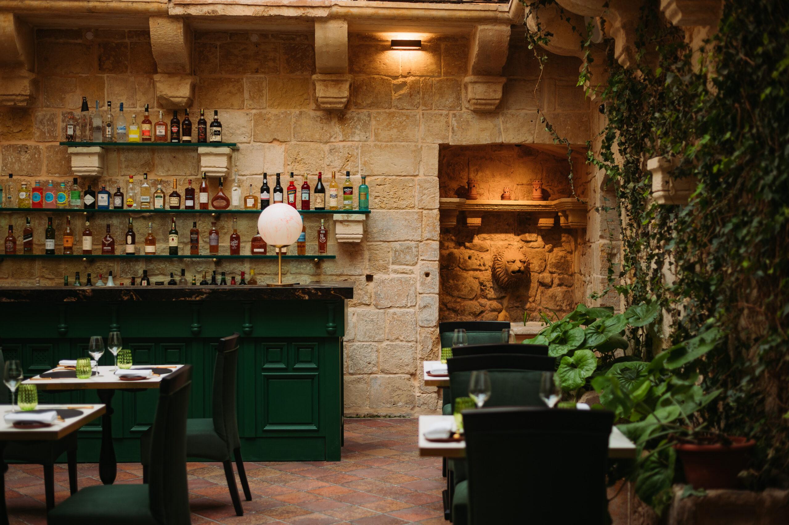 Stone-walled restaurant interior with bar, green joinery and trailing ivy