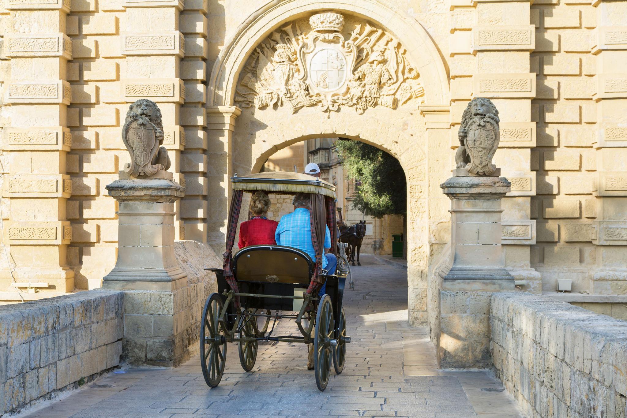 Karozzin horse-drawn carriage passing through Mdina's main gate