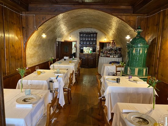 Trentino stube — vaulted stone ceiling, green tiled stove and dark timber panelling