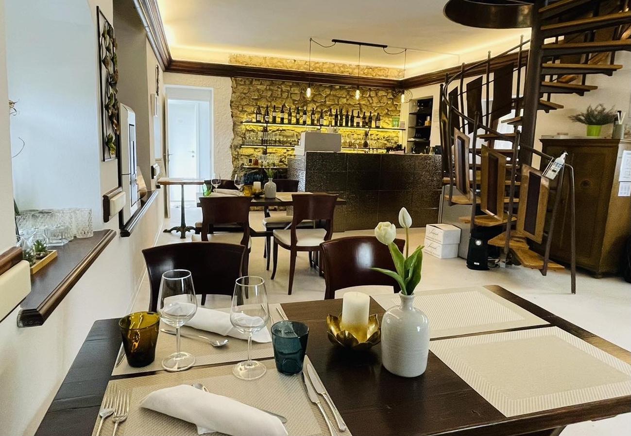 Interior of Gostilna Podfarovž showing set tables, stone wall and wine bar